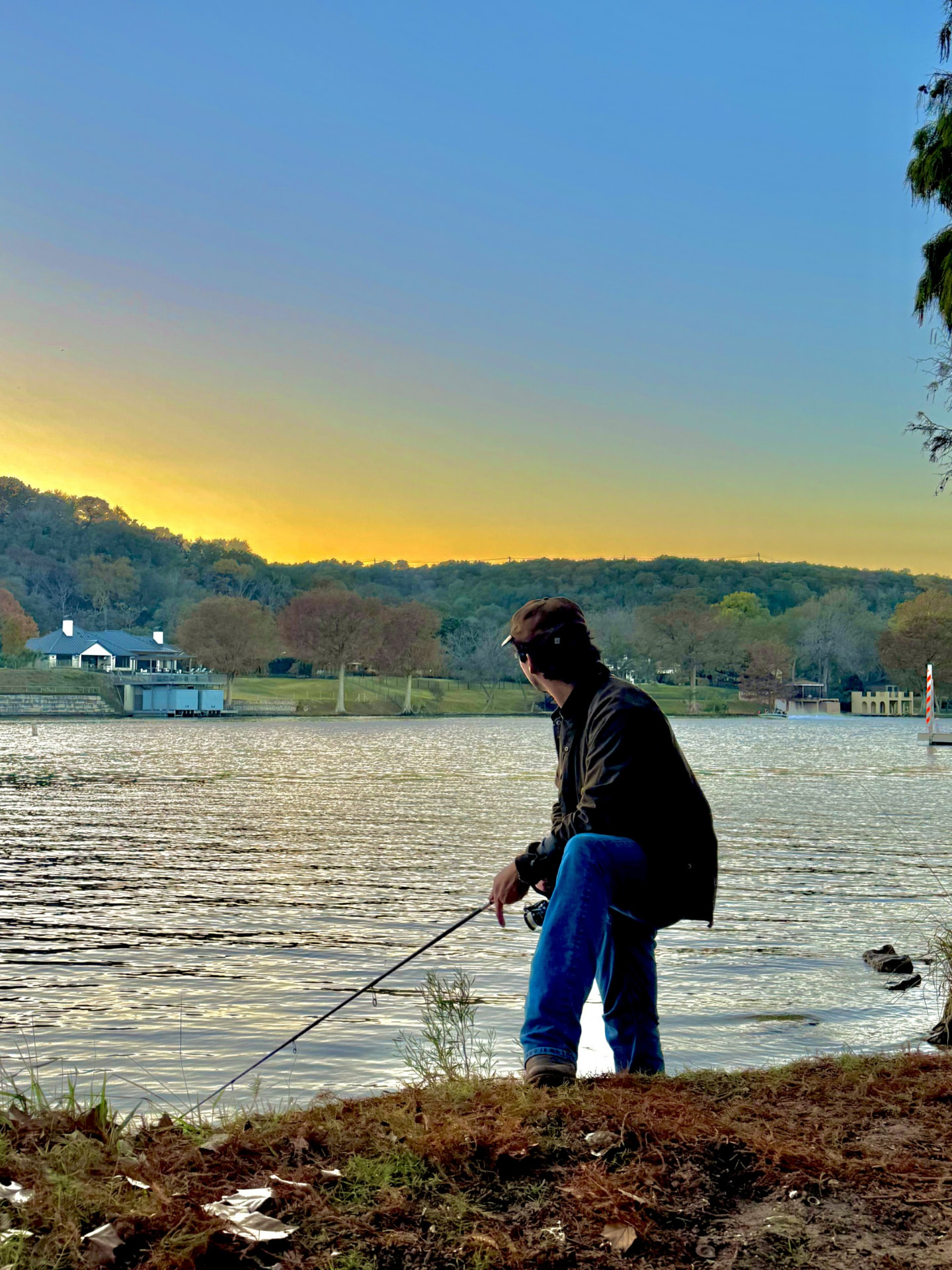 Matthew Vargas fishing from a grassy bank at sunset on a lake outside Austin